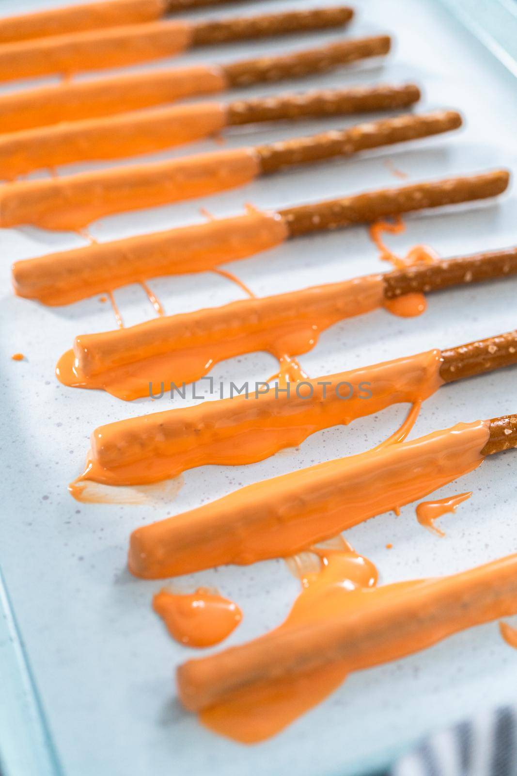 Dipped in chocolate pretzel rods on a baking sheet with parchment paper.