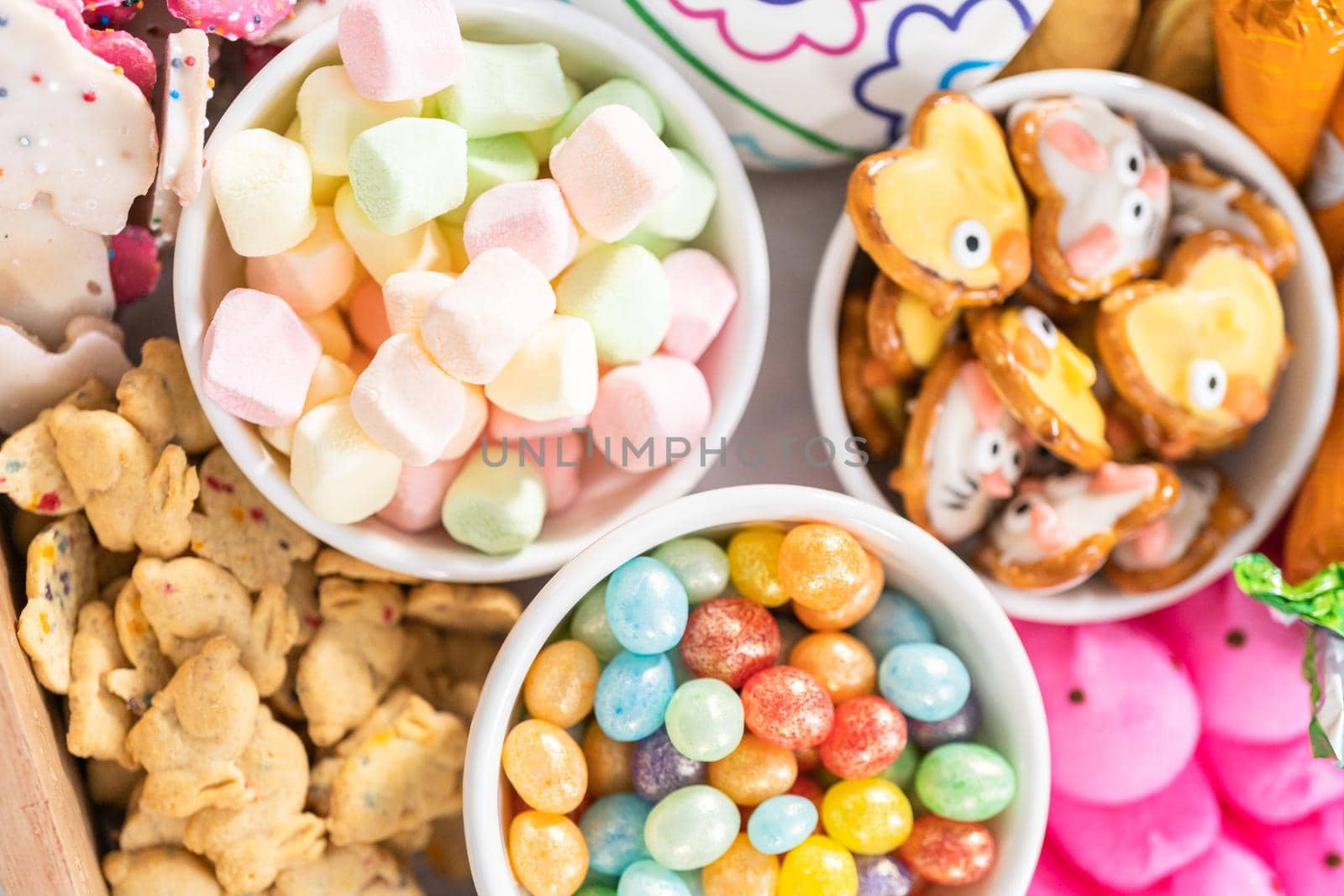 Assembling charcuterie board with Easter candies, cookies, and marshmallows.
