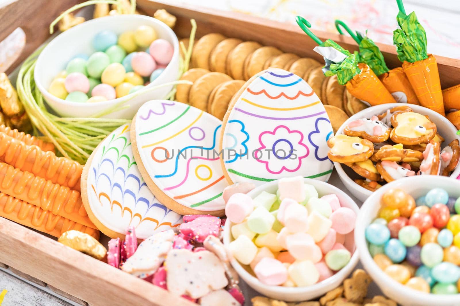 Assembling charcuterie board with Easter candies, cookies, and marshmallows.