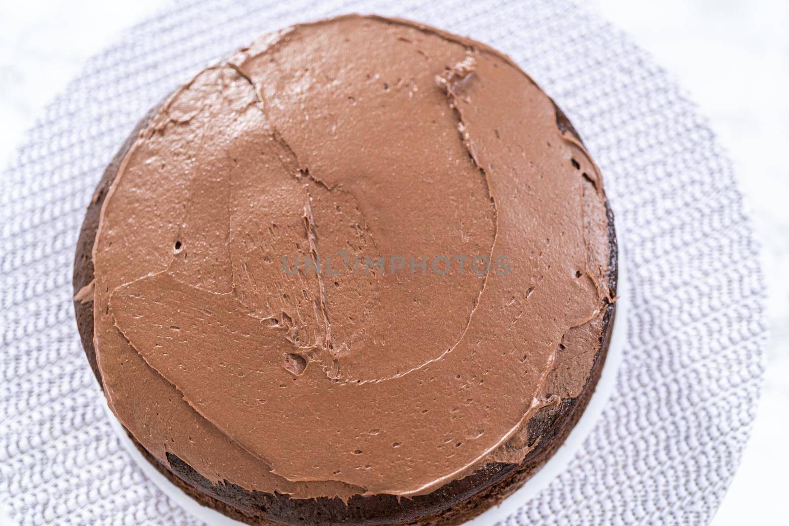 Covering chocolate cake with a crumb layer of chocolate buttercream frosting.