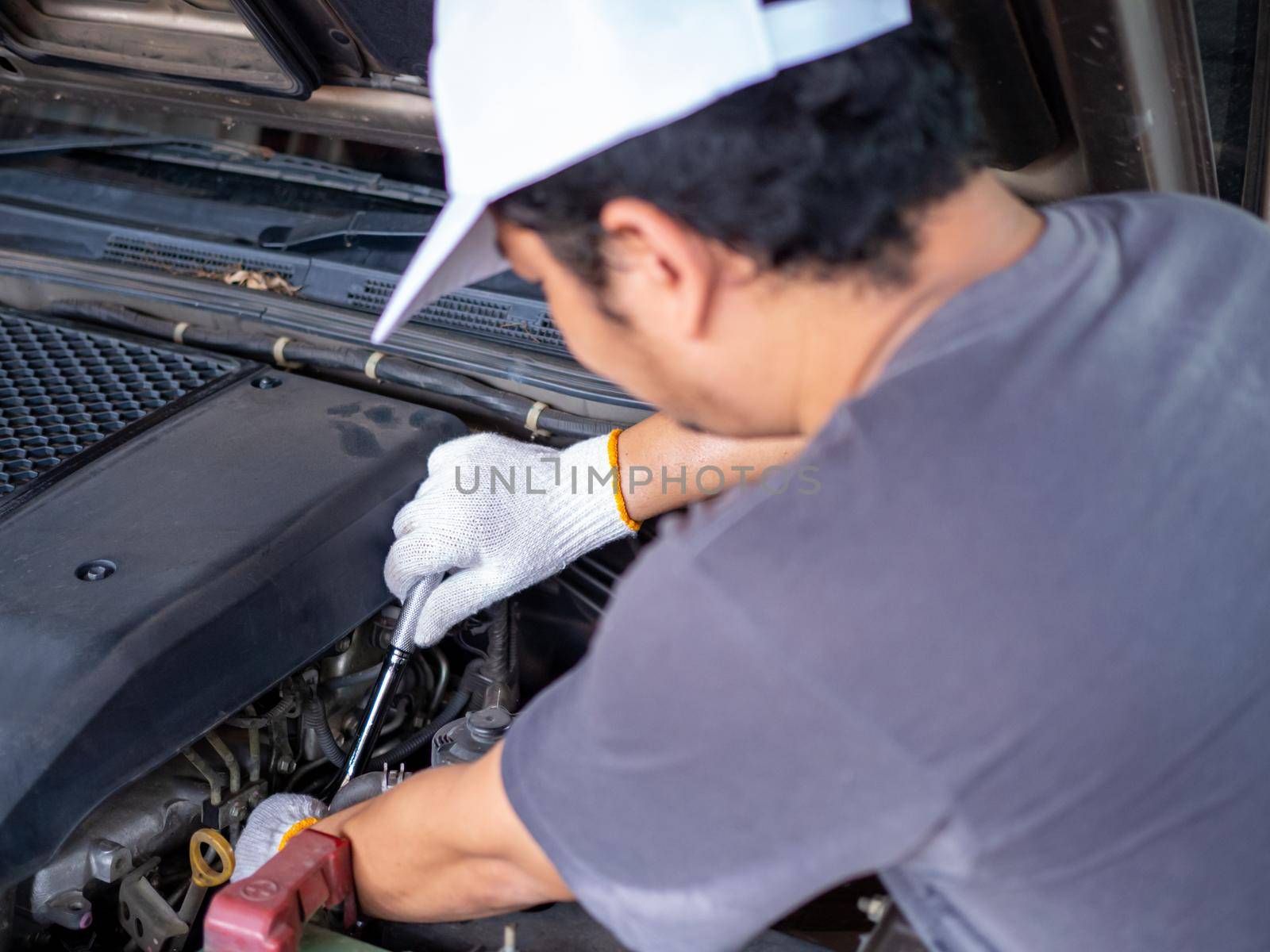 Mechanic holding a block wrench handle while fixing a car.