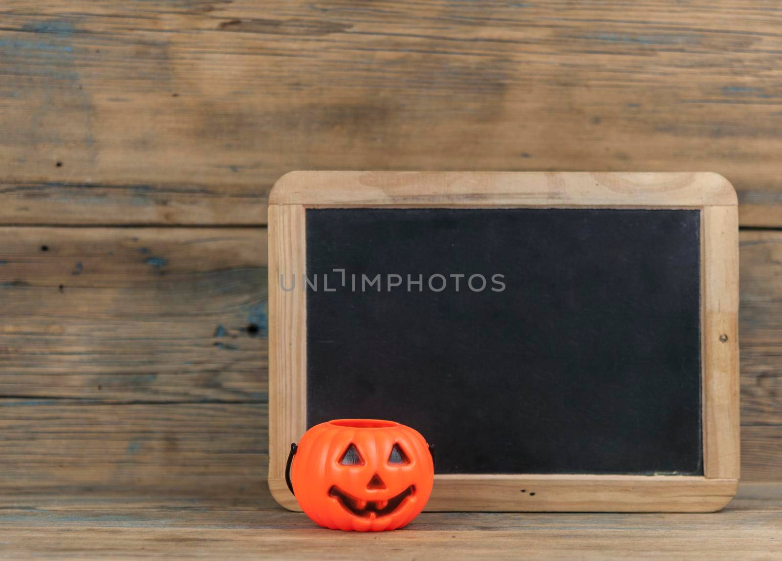 Plastic pumpkin buckets with wood background and blank blackboard by inxti