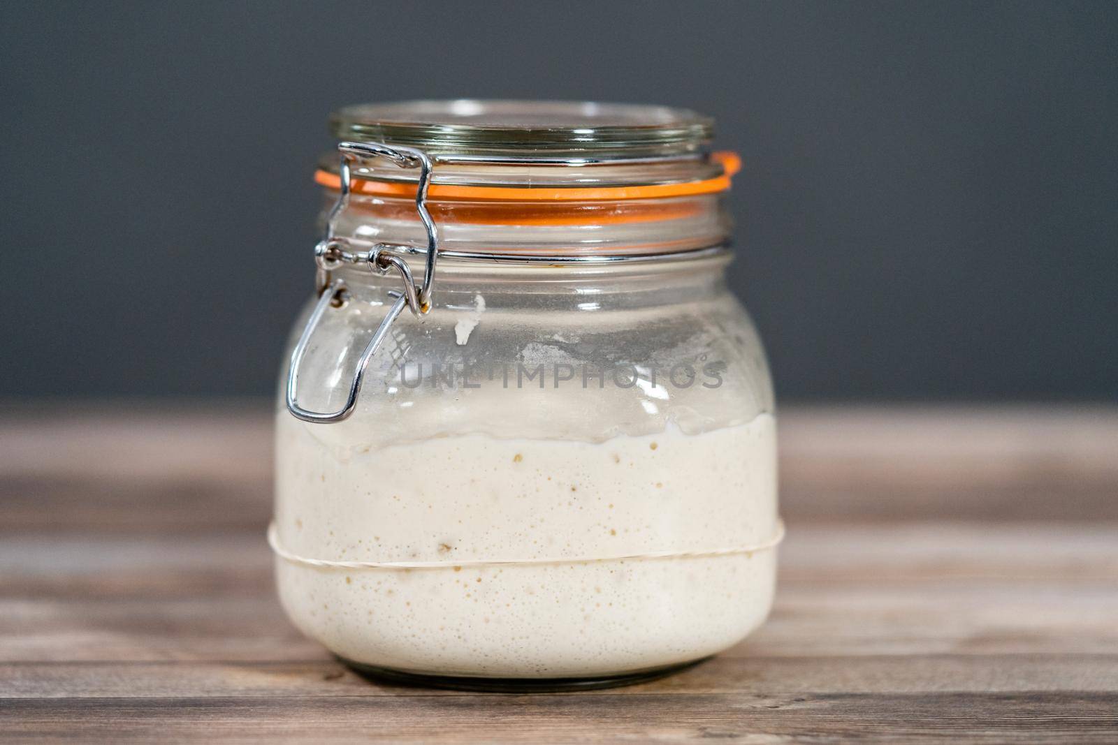 Feeding sourdough starter in a glass mason jar for baking artisan bread.
