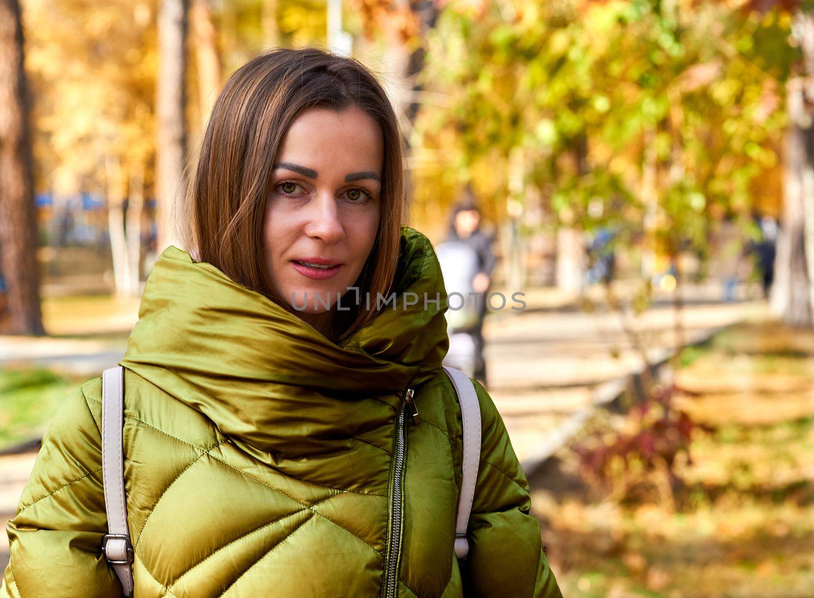 Charming young woman in a green jacket among colorful golden autumn foliage by jovani68