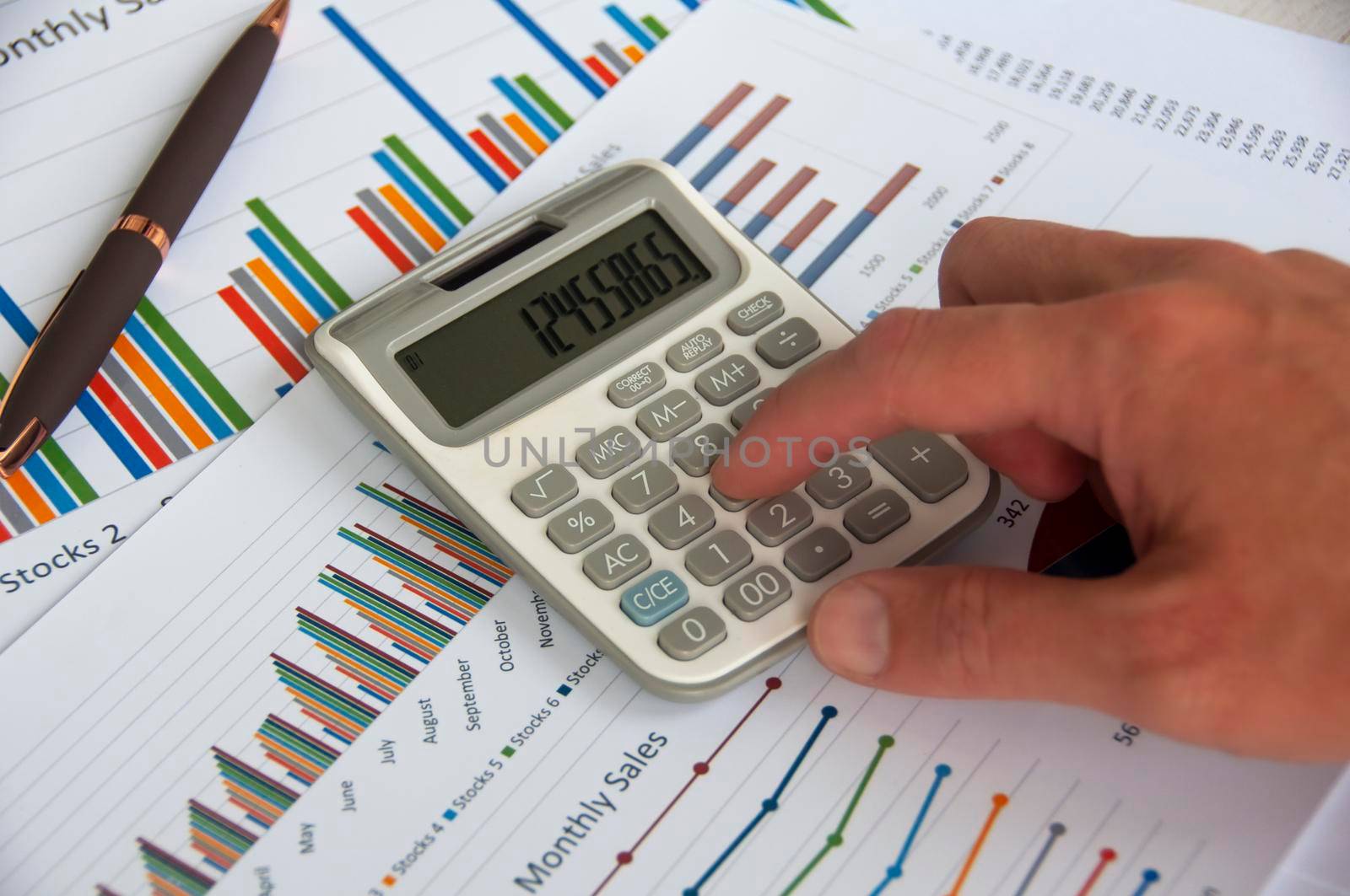 Hand pressing calculator with graph analysis background. Business analysis concept.