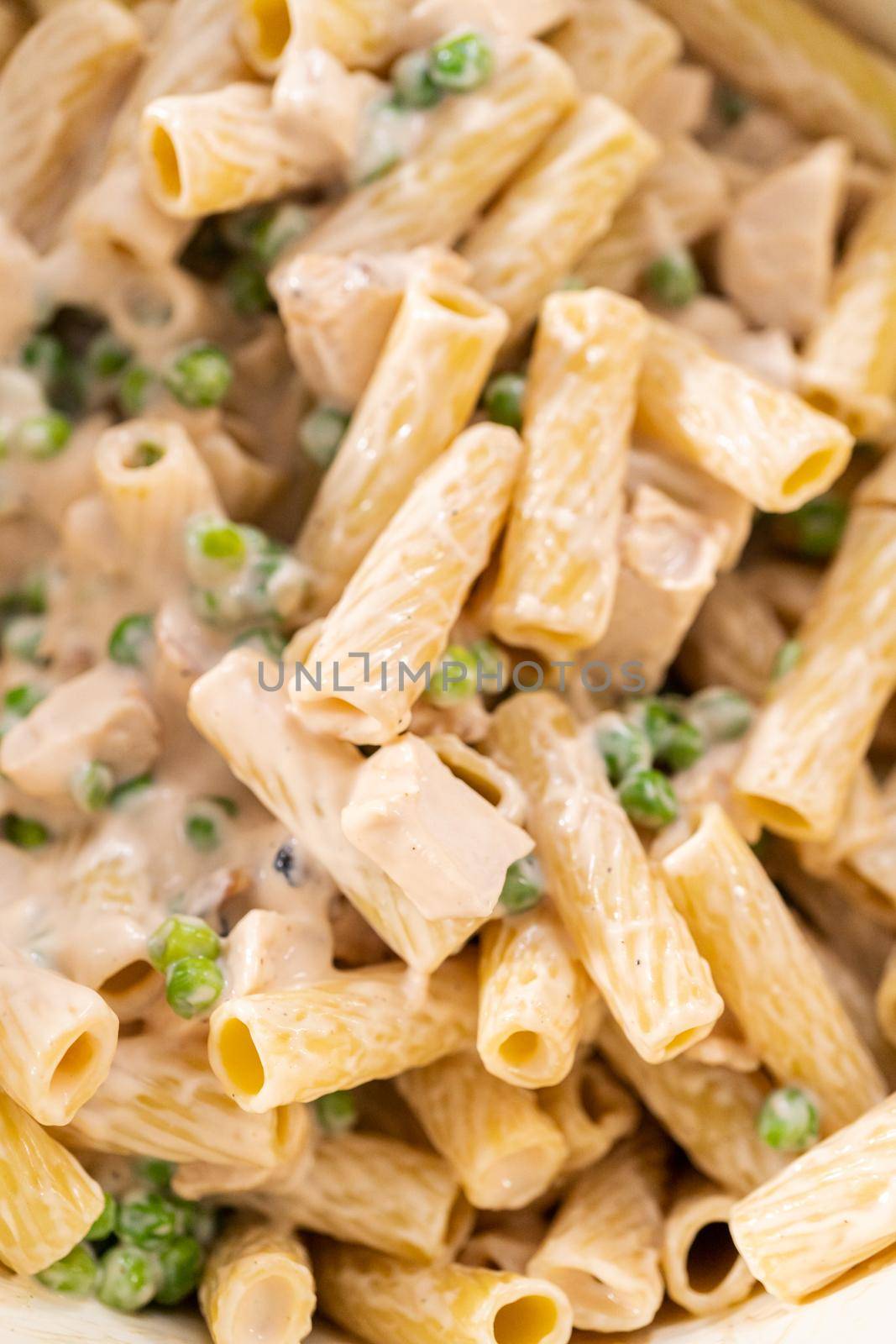Mixing ingredients in an enameled dutch oven to prepare chicken alfredo pasta.