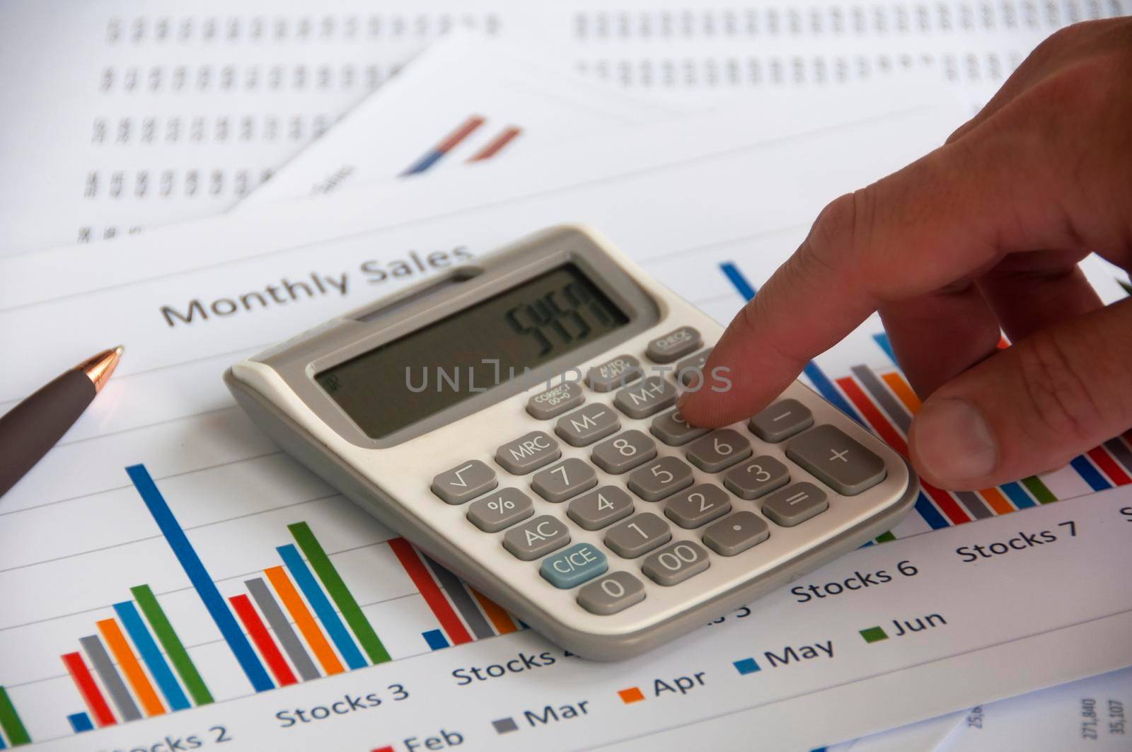 Hand pressing calculator with graph analysis background. Business analysis concept.