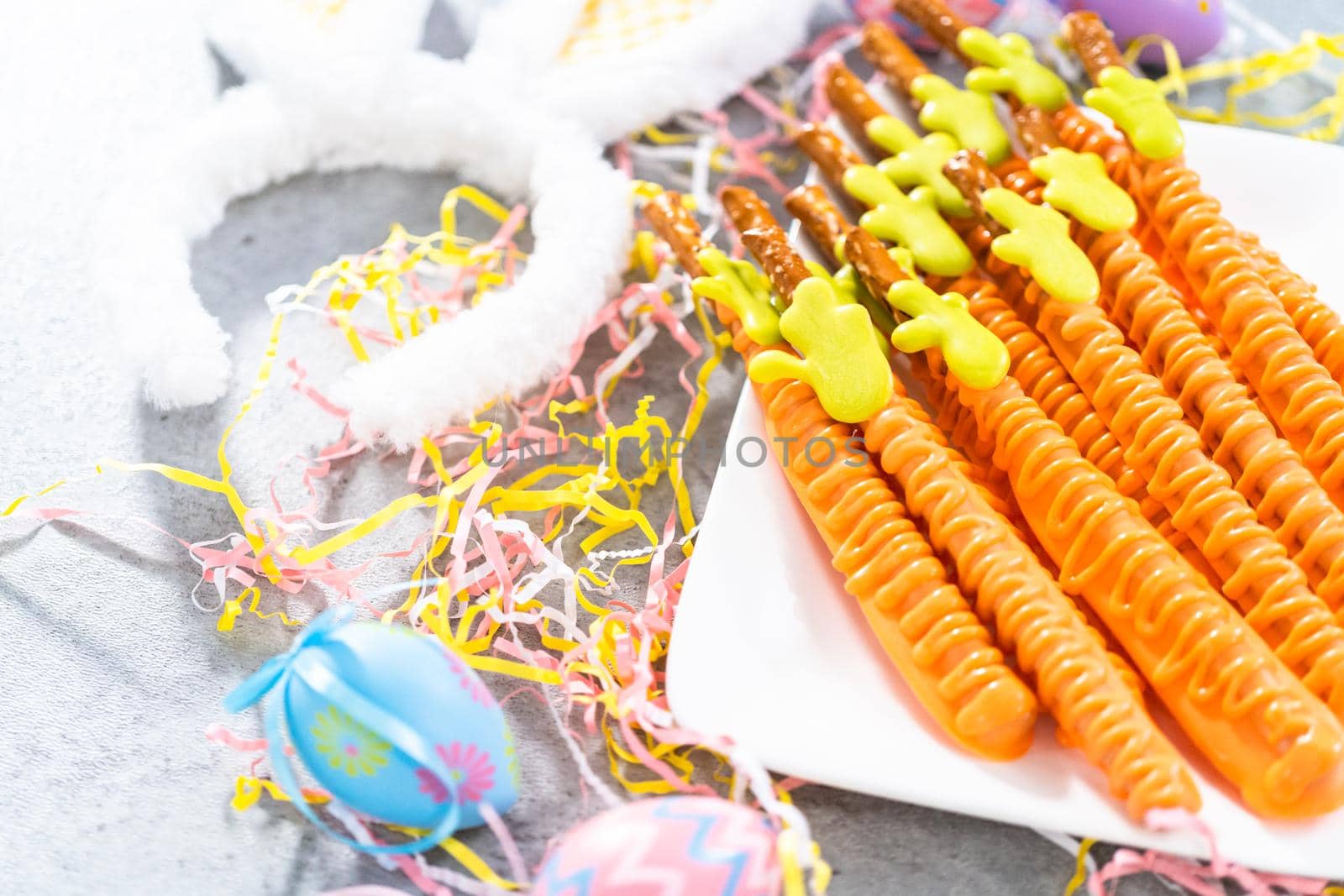 Carrot chocolate-covered pretzels on a white serving plate for the Easter table.