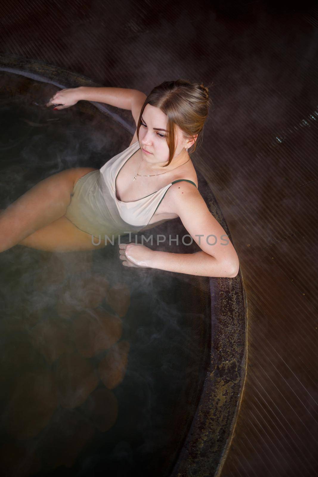 Beautiful figure woman in a swimsuit. Girl in the pool with hot water on the terrace, spa body treatments. Outdoor Jacuzzi. Jacuzzi with a girl. Relax in the open air, wellness. Cottage with spa bath. by Dmitrytph