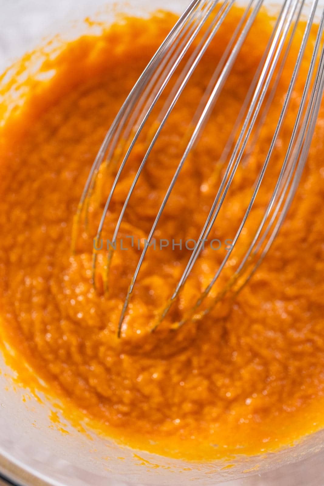 Mixing ingredients in a glass mixing bowl to bake sweet pumpkin bread.