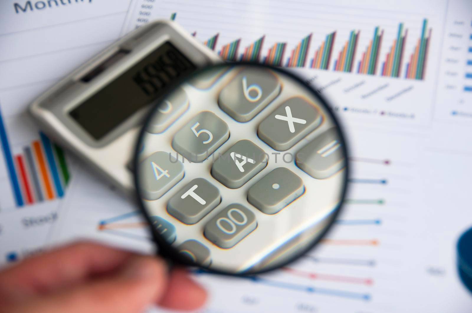 Magnifying glass focusing on TAX work on calculator. Business and tax concept