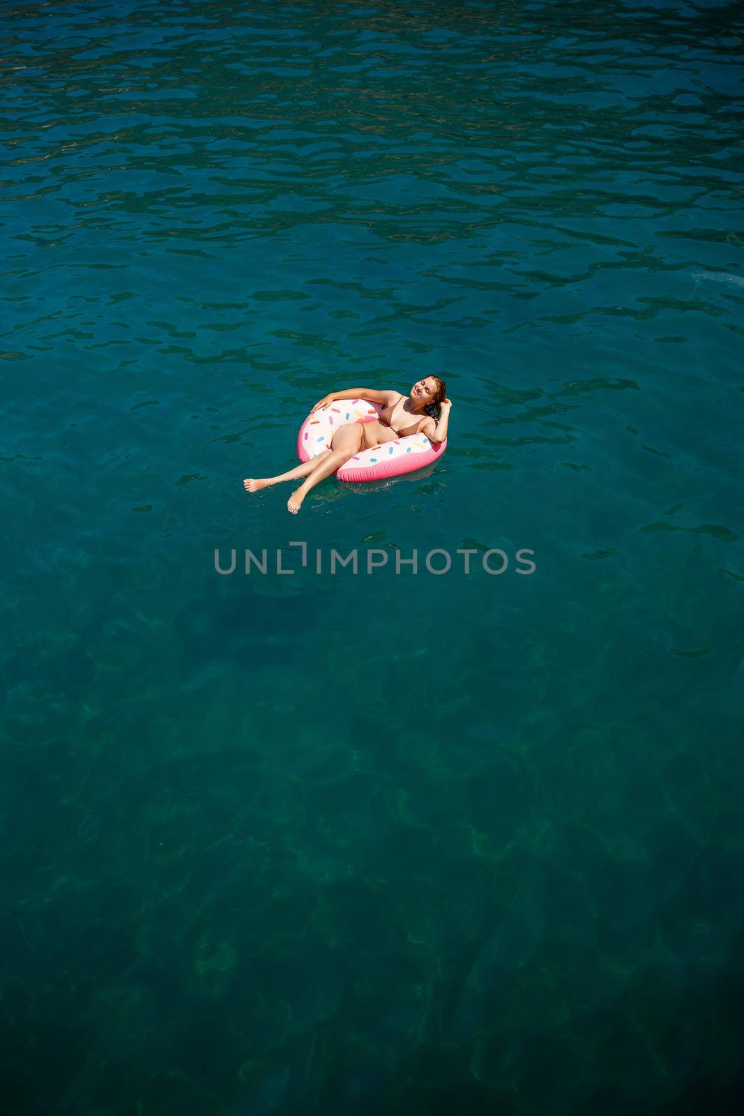 Young woman in a swimsuit swims on an inflatable ring in the sea. Summer vacation concept.