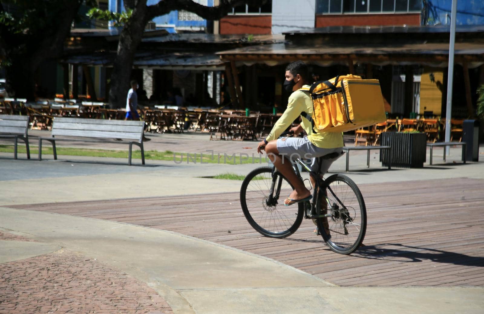 salvador, bahia, brazil - august 13, 2021: Young man is seen with a backpack delivering food on a bicycle in the city of Salvador.
