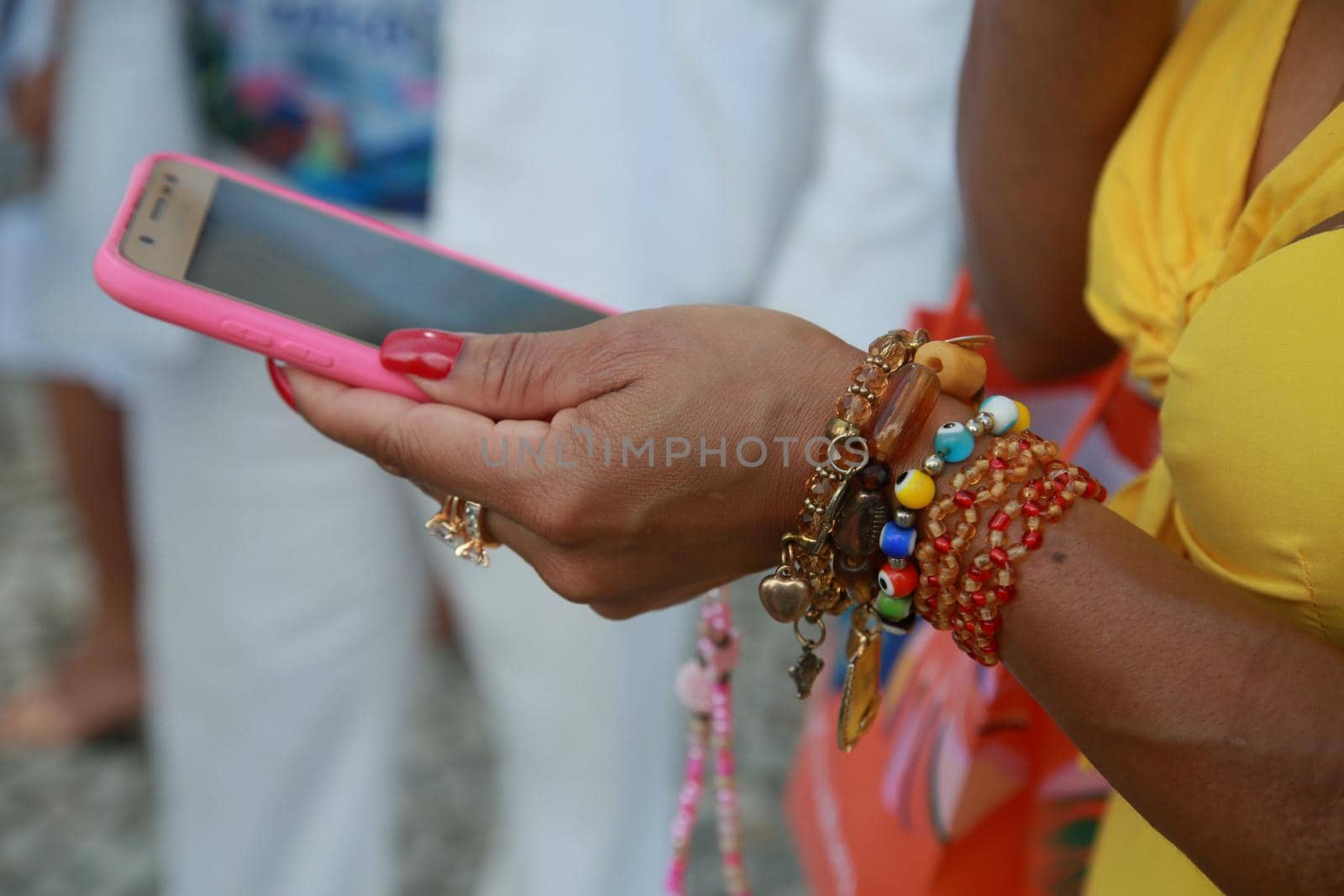 salvador, bahia, brazil - december 8, 2021: hand with bracelets holding on a cell phone in the city of Salvador.