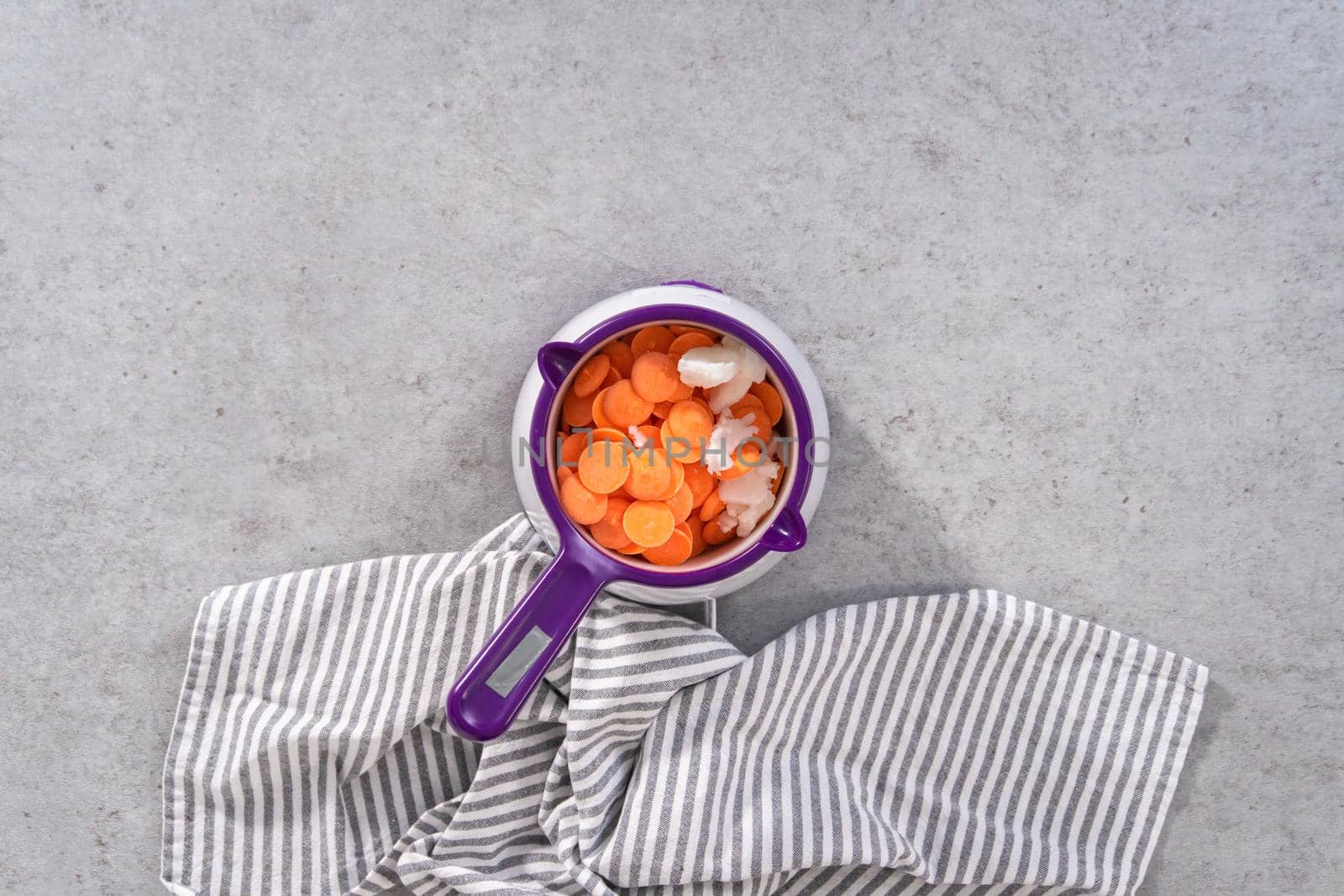 Flat lay. Melting color chocolate chips in a candy melting pot to make carrot chocolate-covered pretzels.
