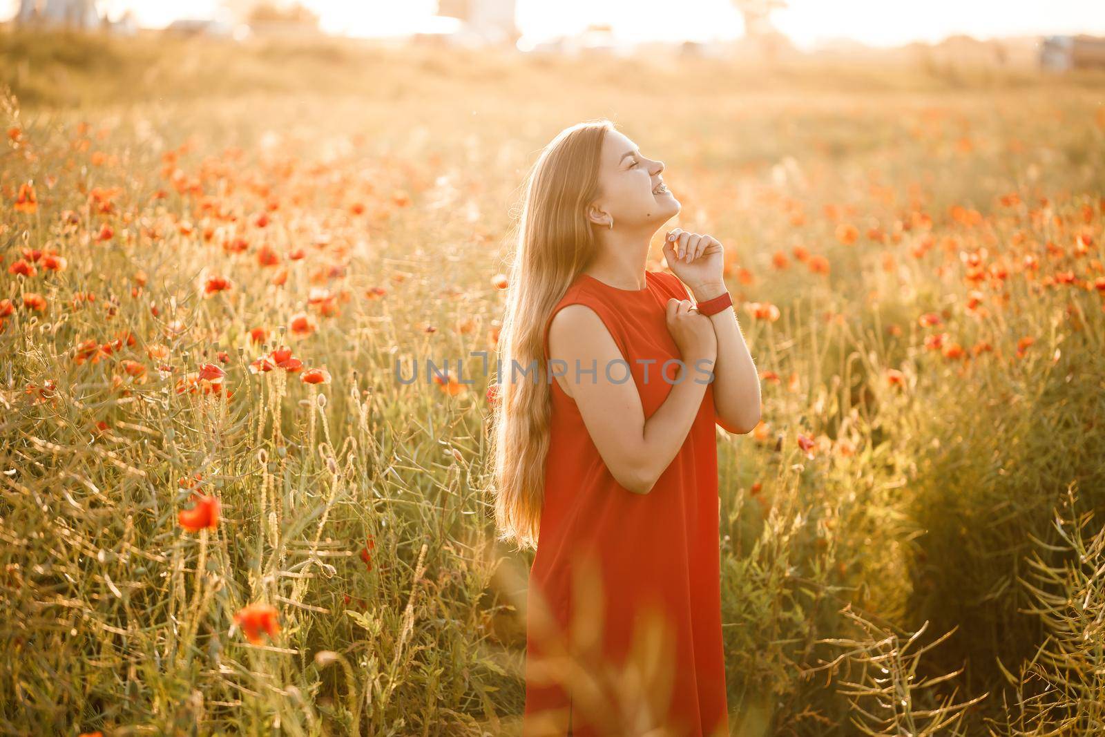 Beautiful woman in a red dress in a field of blooming poppies. Selective focus