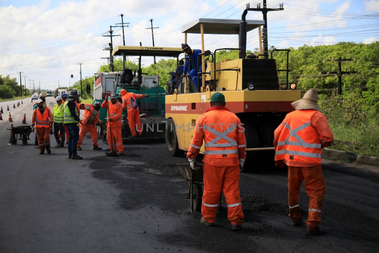 camacari, bahia, brazil - august 24, 2021: workers are seen doing asphalt recap of the access lane to the industrial hub of the city of Camacari.
