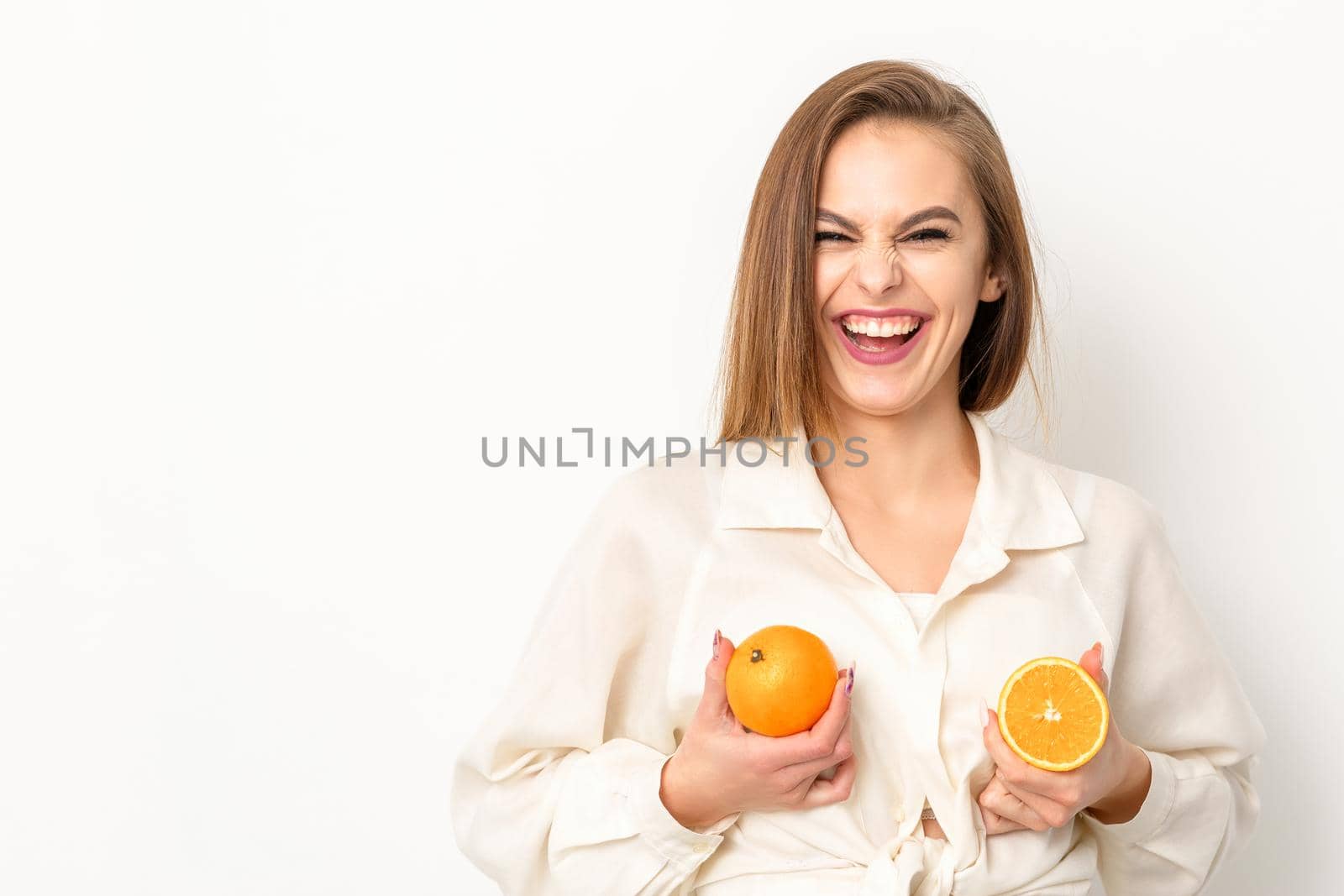 Young Caucasian smiling woman holding slices orange over isolated white background, breast health concept