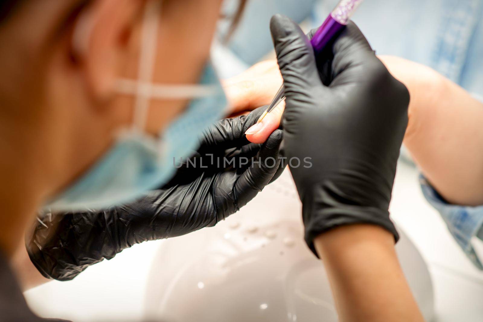 Manicure painting art. Manicure master drawing on the nail tip with a thin brush, close up