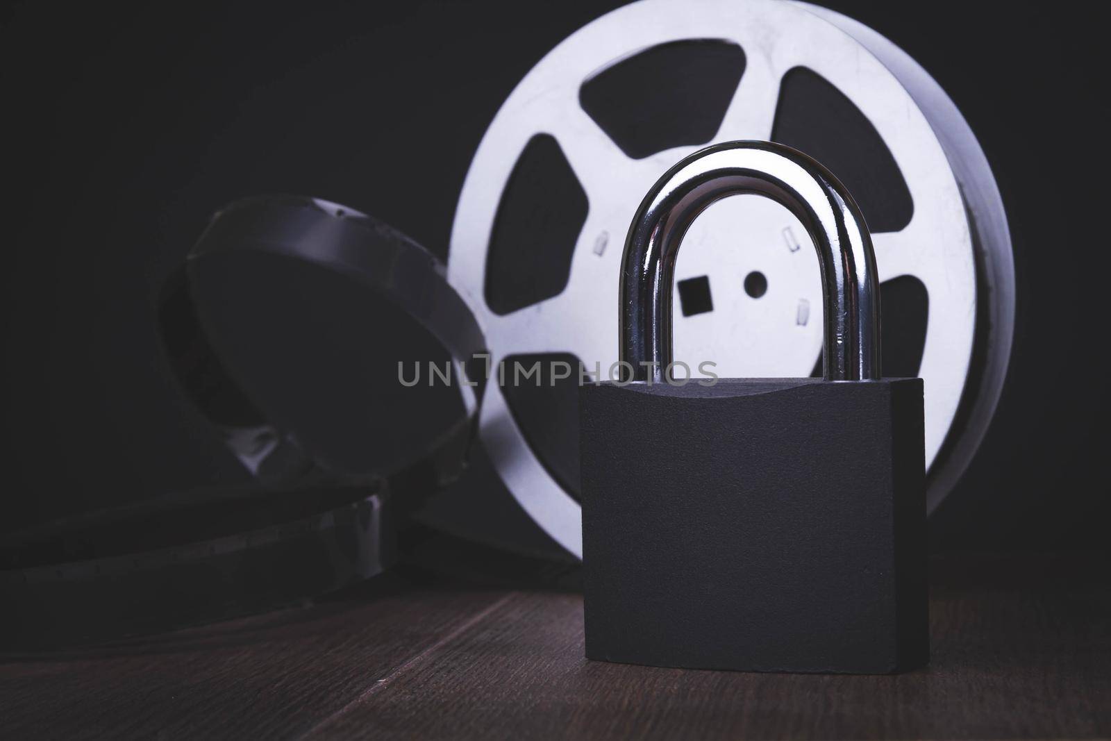 Movie screening ban. Forbidden film. Indoor cinema.Film reel and padlock on a black background. Limited screening of the film in cinemas.