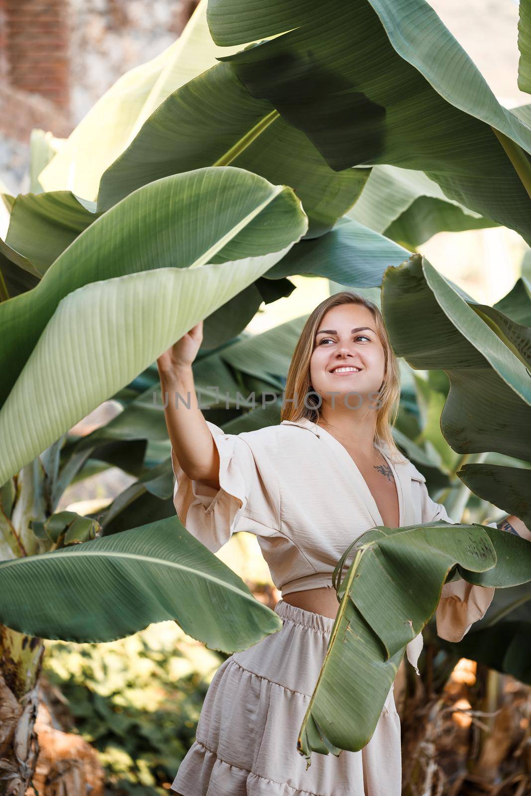 Beautiful woman in the jungle. A resort or hotel with tropical trees and plants. Woman with near banana leaf. Girl on vacation in the rainforest