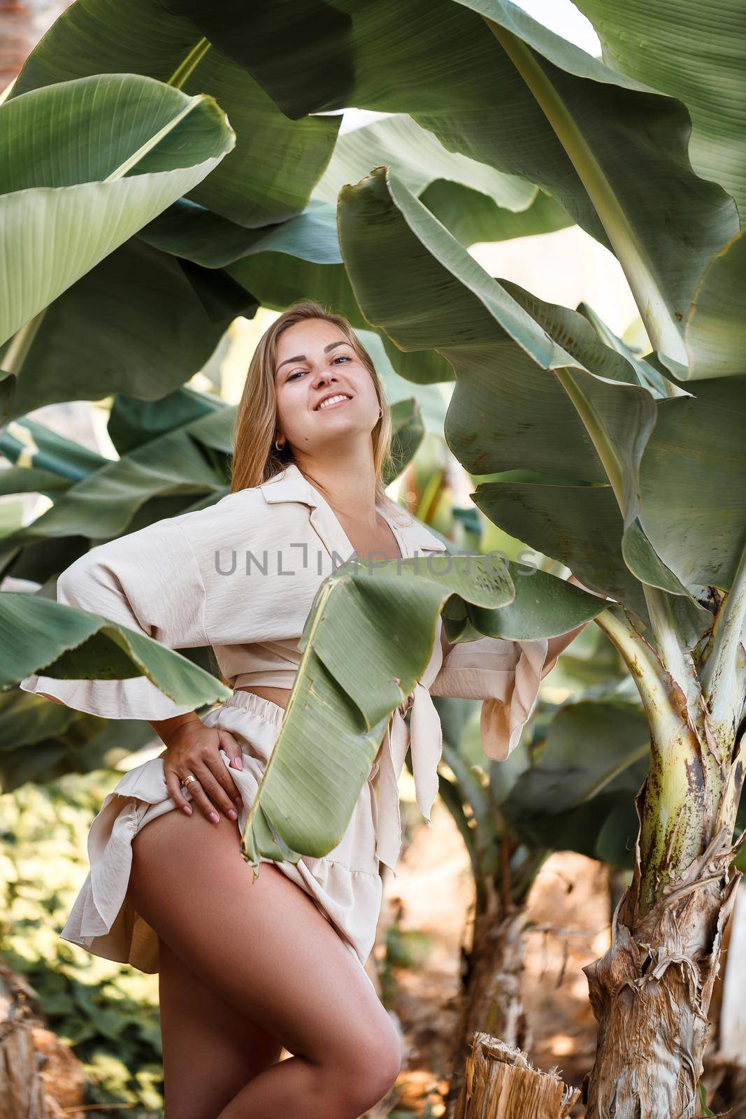 Beautiful woman in the jungle. A resort or hotel with tropical trees and plants. Woman with near banana leaf. Girl on vacation in the rainforest. Selective focus