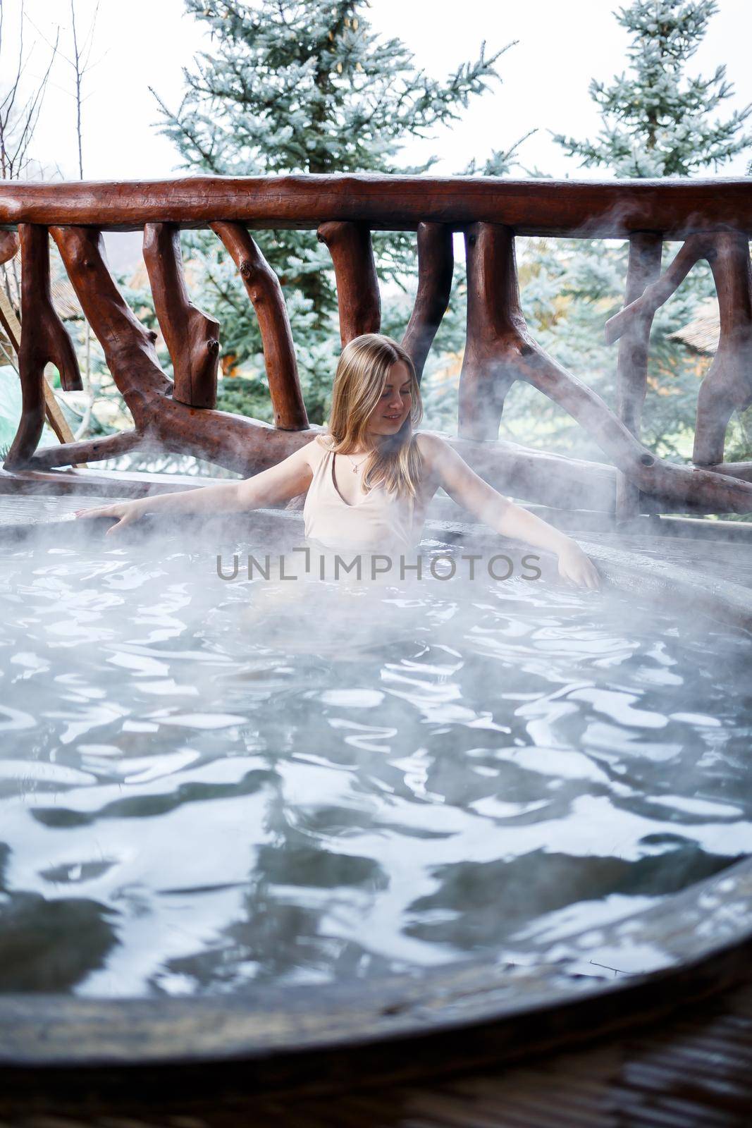 Beautiful figure woman in a swimsuit. Girl in the pool with hot water on the terrace, spa body treatments. Outdoor Jacuzzi. Jacuzzi with a girl. Relax in the open air, wellness. Cottage with spa bath by Dmitrytph