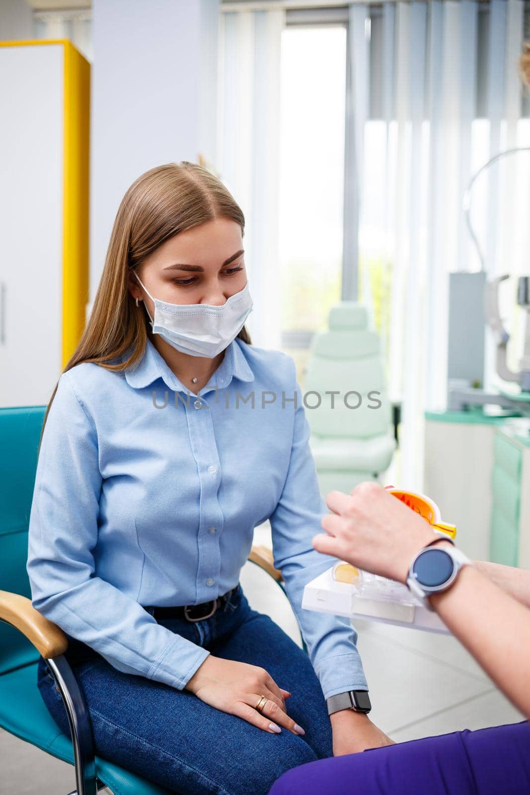 Young woman sitting in armchair looking at slit lamp during medical examination in eyes