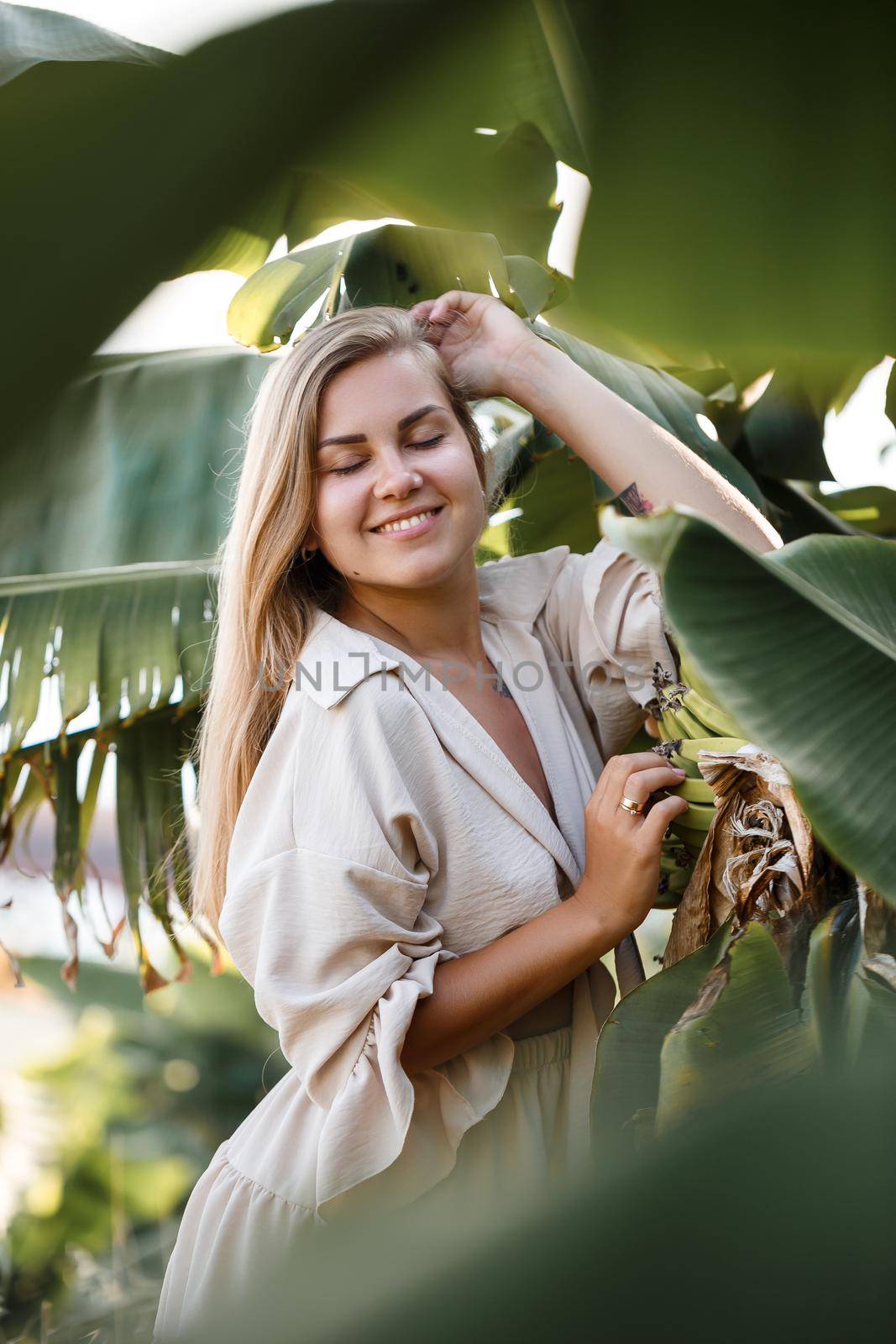 Exotic tropical woman near green leaves of banana bush. Tropical island girl on vacation
