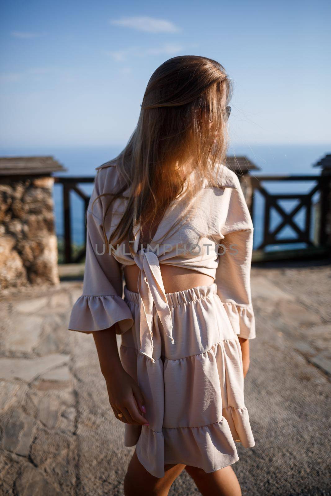 Young woman with long blond hair in a light top and skirt walks on a summer sunny day