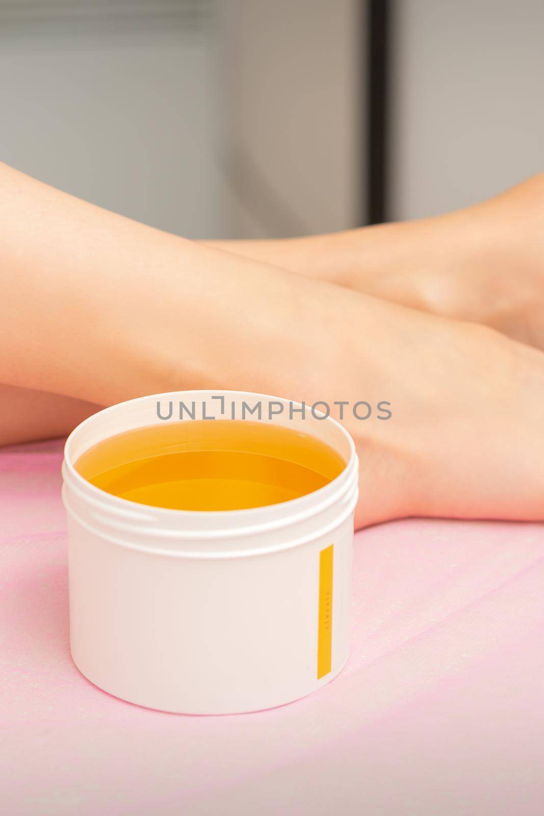 Woman legs with a white jar of wax sugaring before hair removal at the spa. by okskukuruza