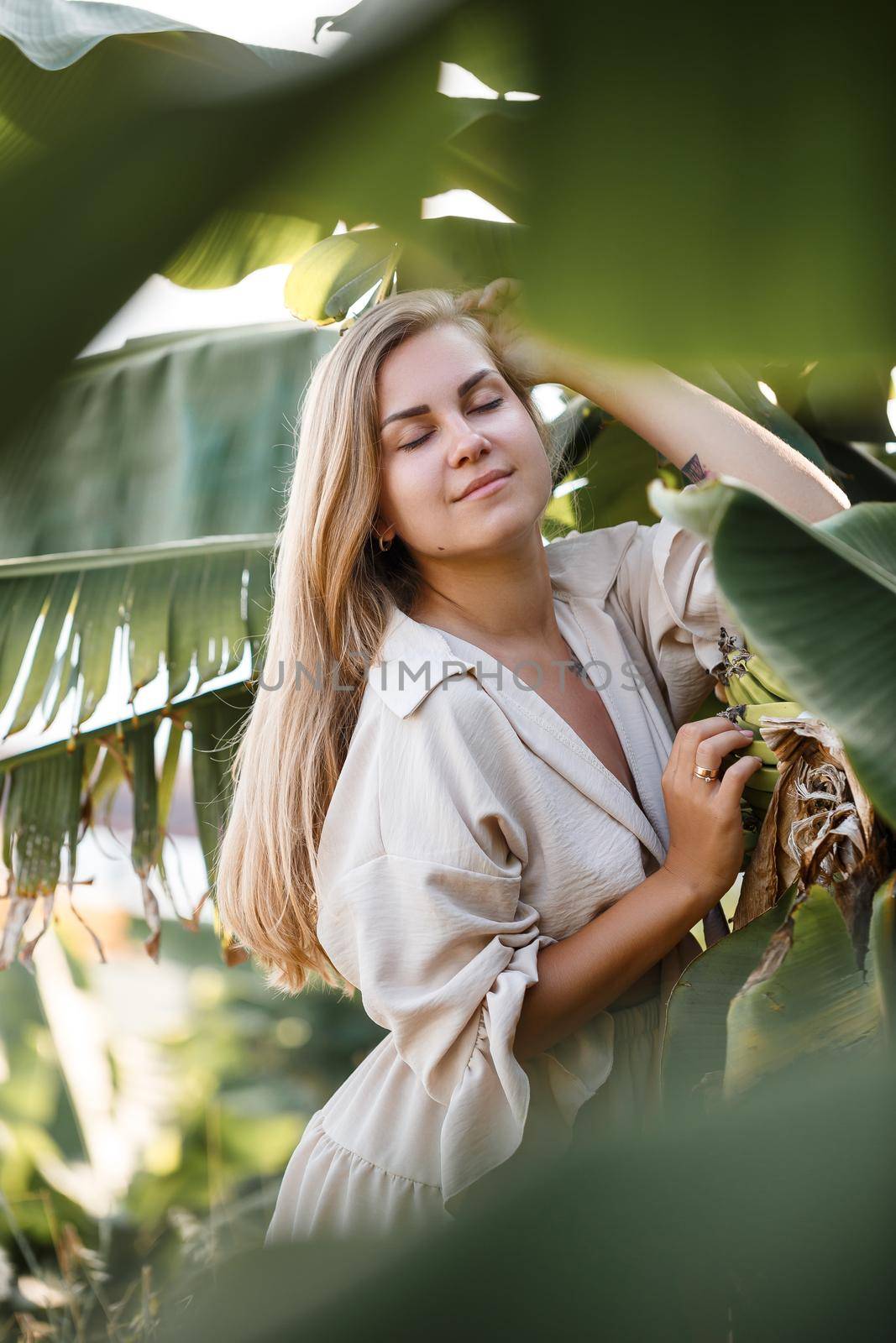 Exotic tropical woman near green leaves of banana bush. Tropical island girl on vacation