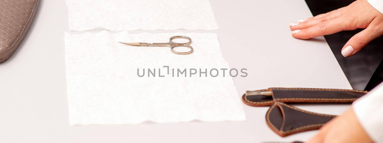 Hands of manicure master prepare nail care tools on a white table