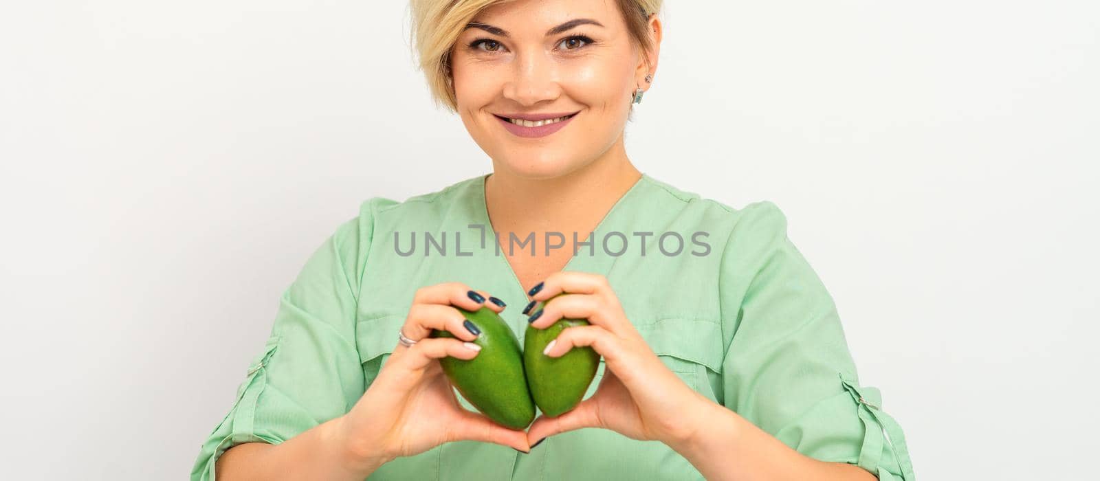 Female nutritionist doctor wearing green workwear holding green organic avocado fruit. Healthy lifestyle concept. by okskukuruza