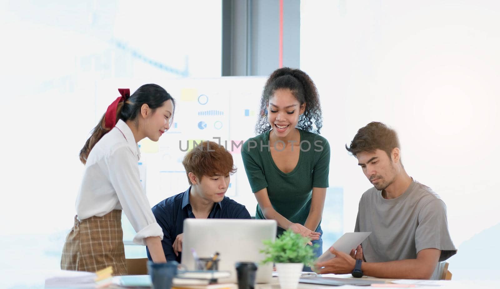 Group of young asian business people in smart casual wear working together in creative office using laptop. by wichayada