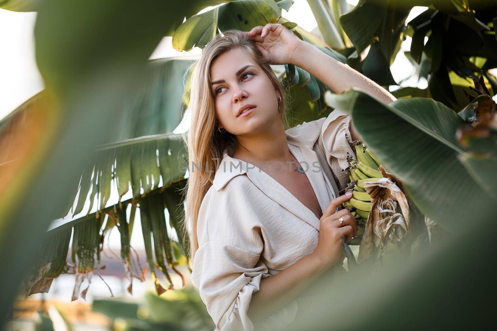 Exotic tropical woman near green leaves of banana bush. Tropical island girl on vacation