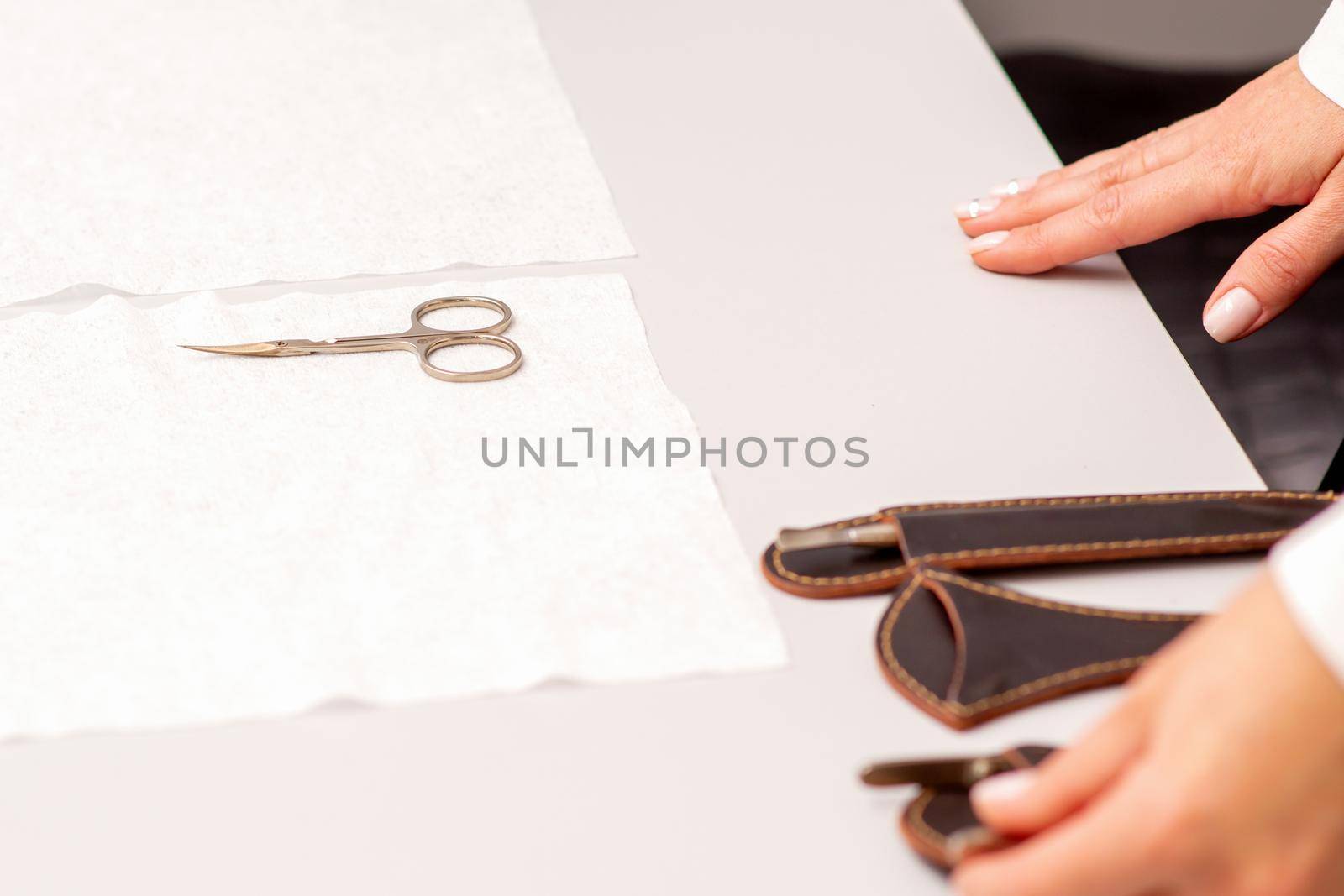 Hands of manicure master prepare nail care tools on a white table