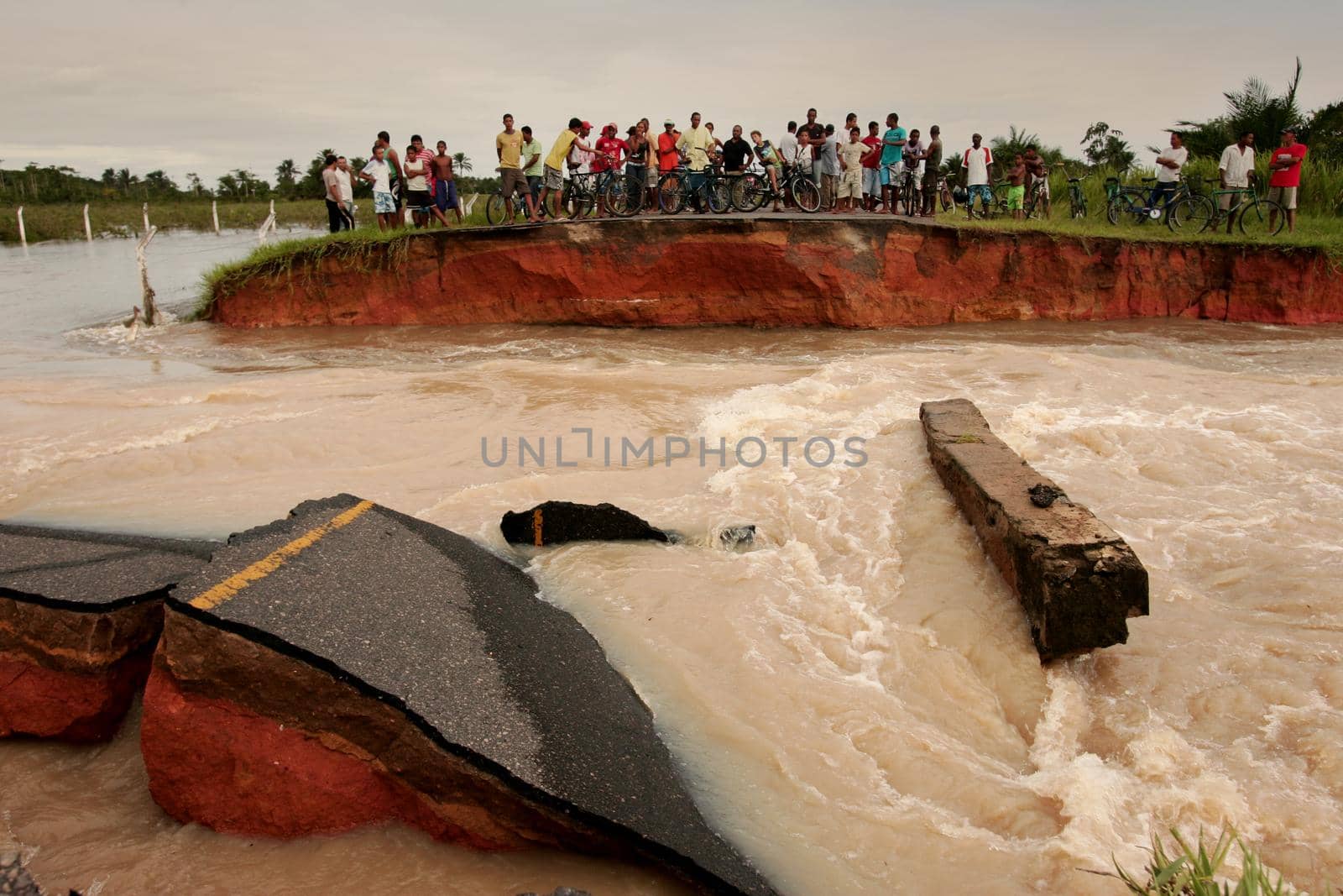 prado, bahia, brazil - april 7, 2010: people trying to cross a road destroyed due to flooding of a river in the city of Prado