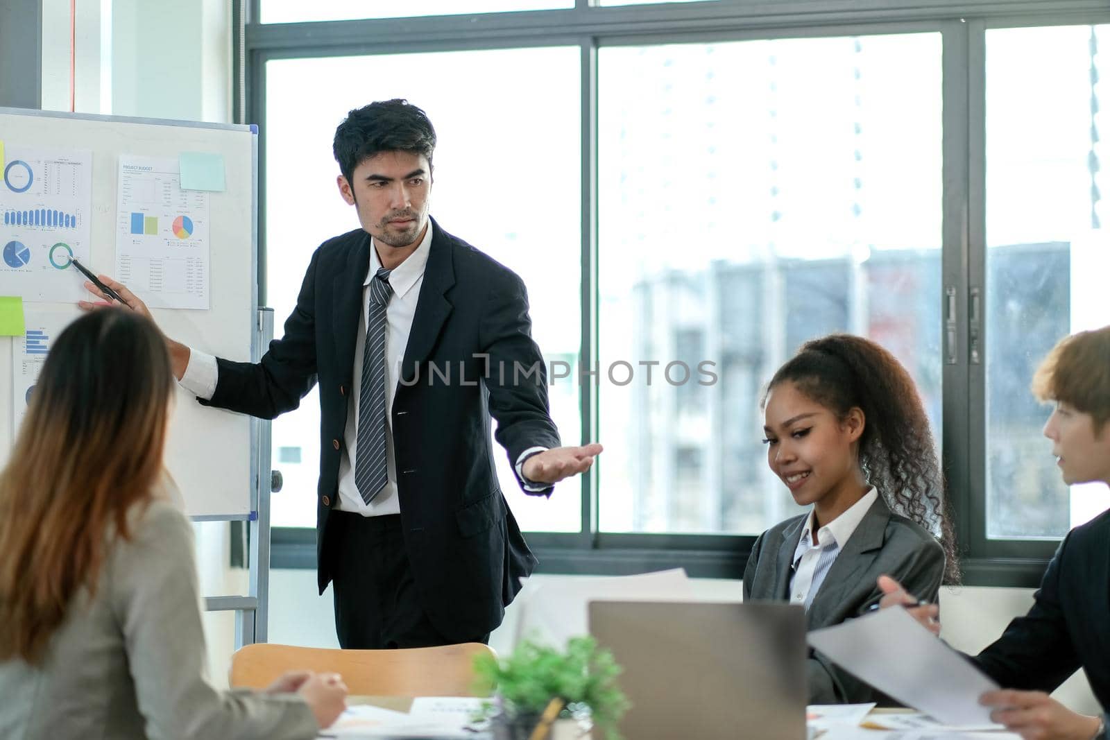 group of young creative asian people doing brainstorming meeting colleagues in board room discussing project. woman standing at white board give presentation.