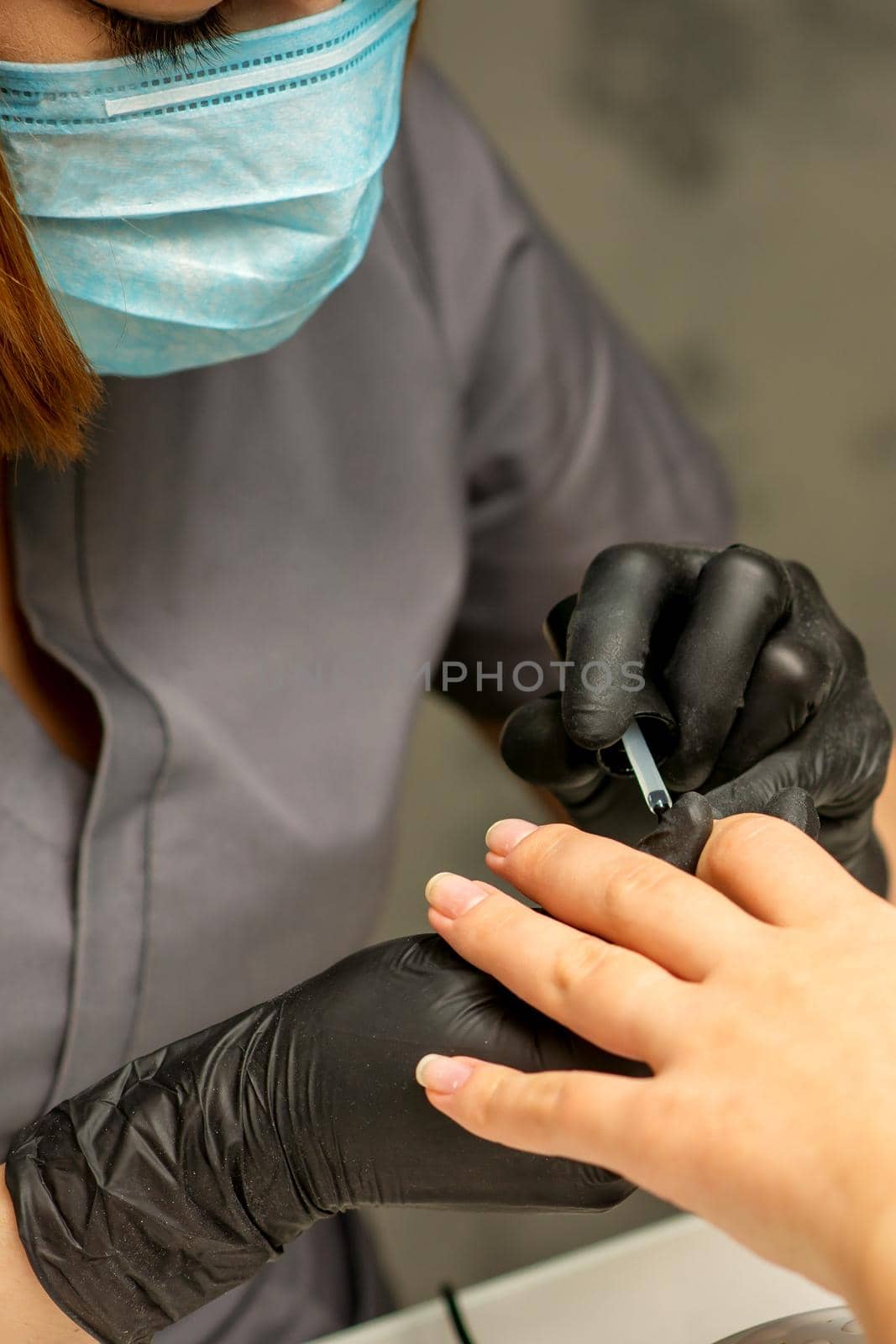 Manicure painting process. Manicure master paint the nails with transparent varnish in a nail salon, close up. by okskukuruza