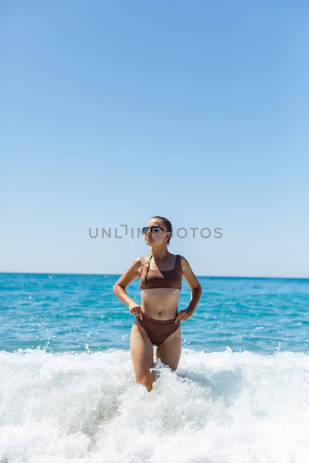 Beautiful woman in a swimsuit and walks on the sand on the beach in Turkey. Holidays in turkey. Photographed with the sea and waves in the background. Selective focus
