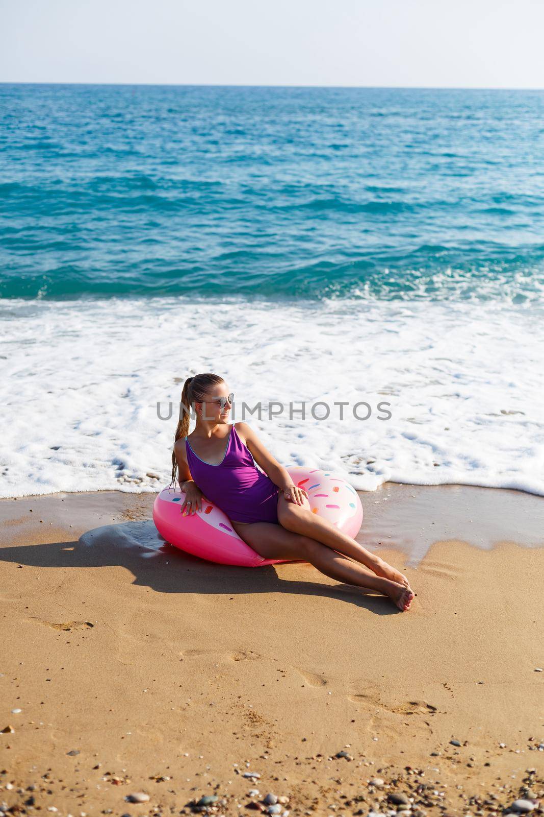 Vacation at the sea. Beautiful slender woman in a swimsuit with an inflatable ring on the beach. Girl resting in the summer on the turkish coast by Dmitrytph