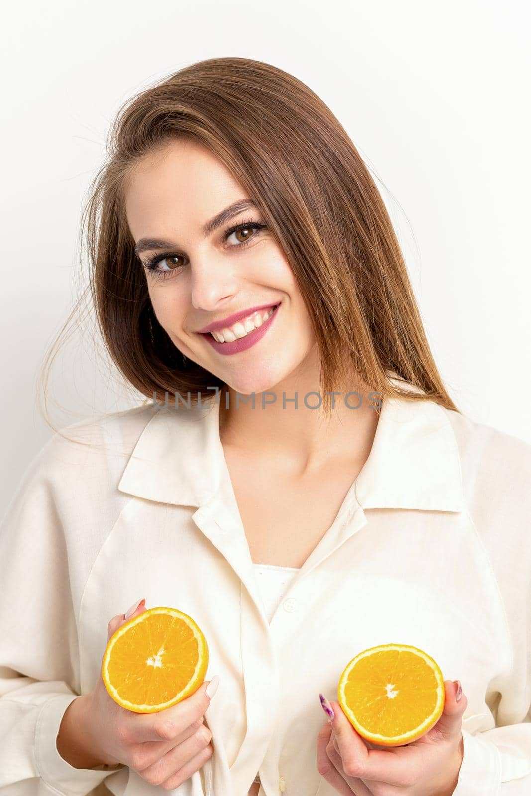 Young Caucasian smiling woman holding slices orange over isolated white background, breast health concept