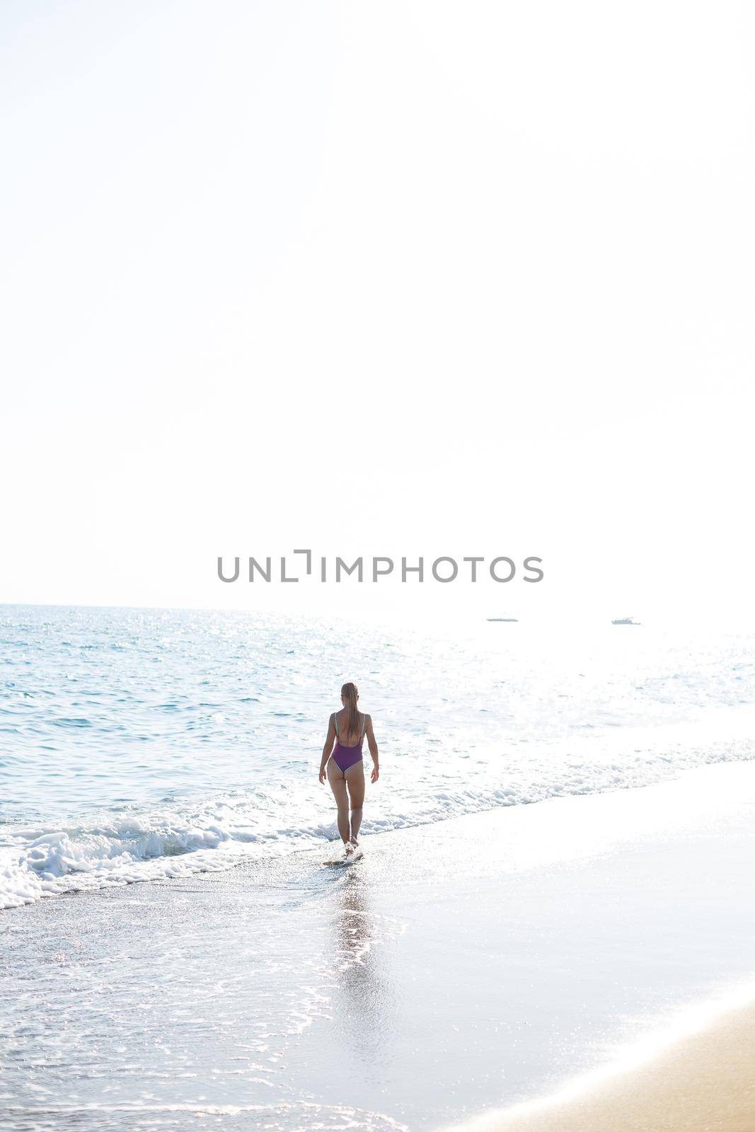 Beautiful woman with a toned body in a bright swimsuit walks along the sandy beach. Summer vacation at the sea. Mediterranean Turkish Sea. Selective focus by Dmitrytph