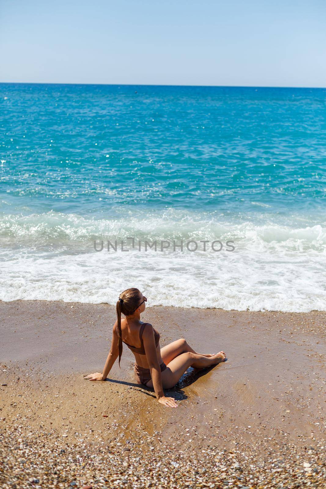 Summer lifestyle. Beautiful woman with a slim tanned body in a bikini swimsuit enjoying life and lying on the sand on the beach of a tropical island. Selective focus by Dmitrytph