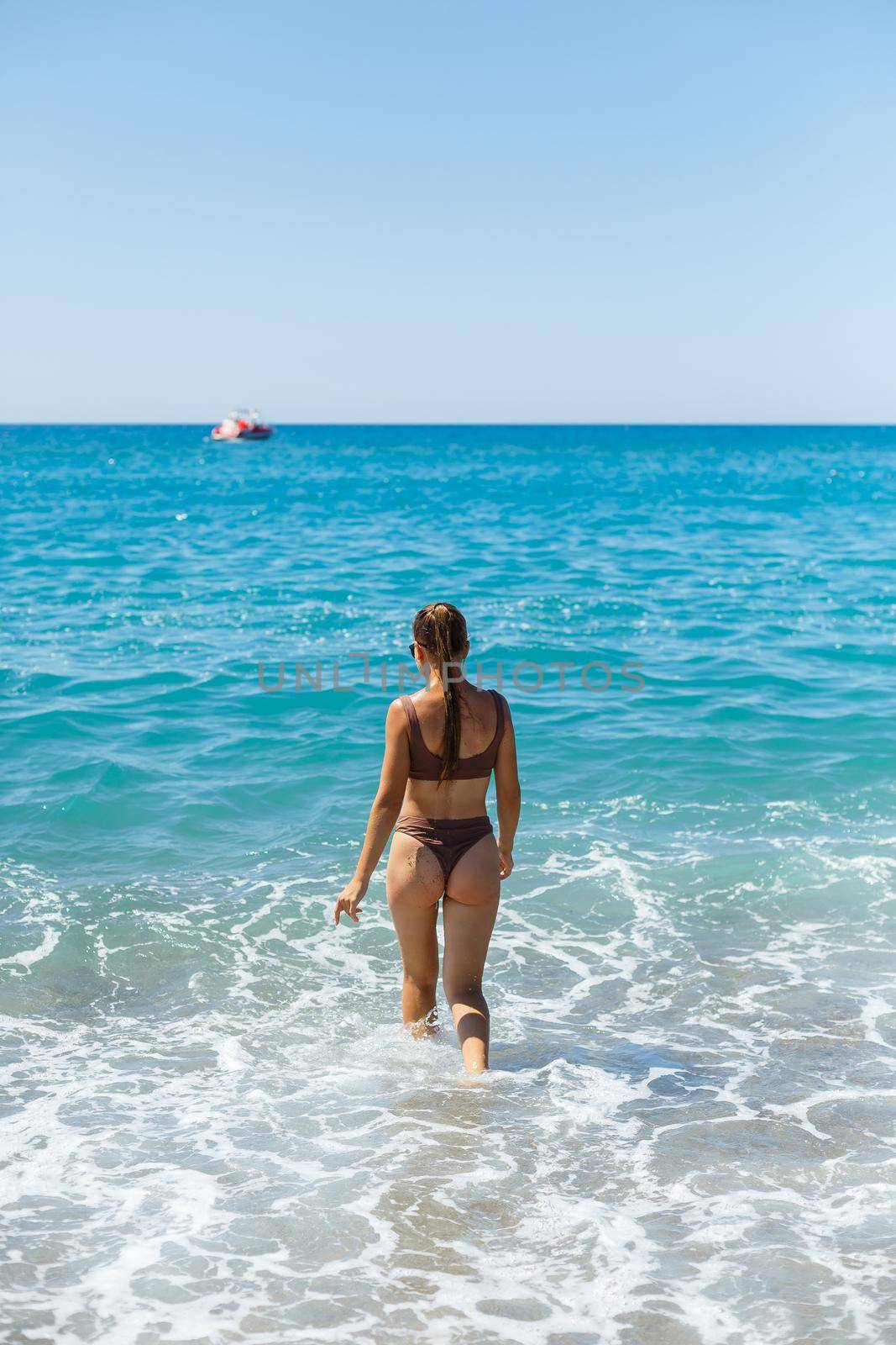 Young woman with blond hair posing and resting on the ocean. A beautiful athletic body of a tourist on the island. Selective focus.