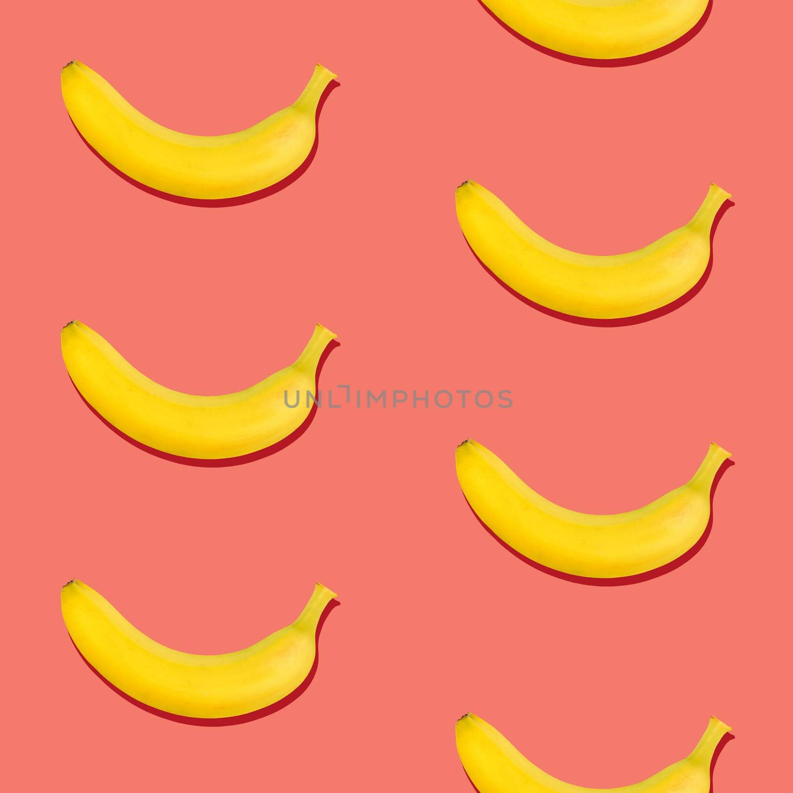 Seamless pattern of fresh ripe yellow bananas on coral pink background