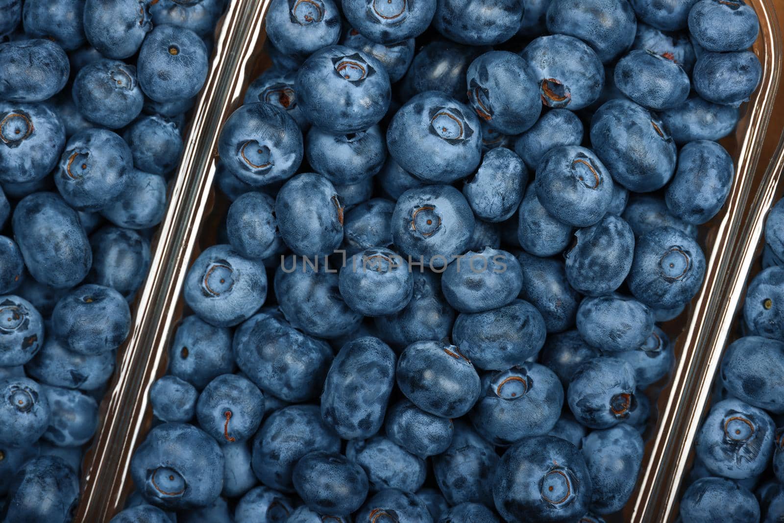 Close up fresh blueberry berries in plastic containers in brown cardboard box on retail display, elevated top view, directly above
