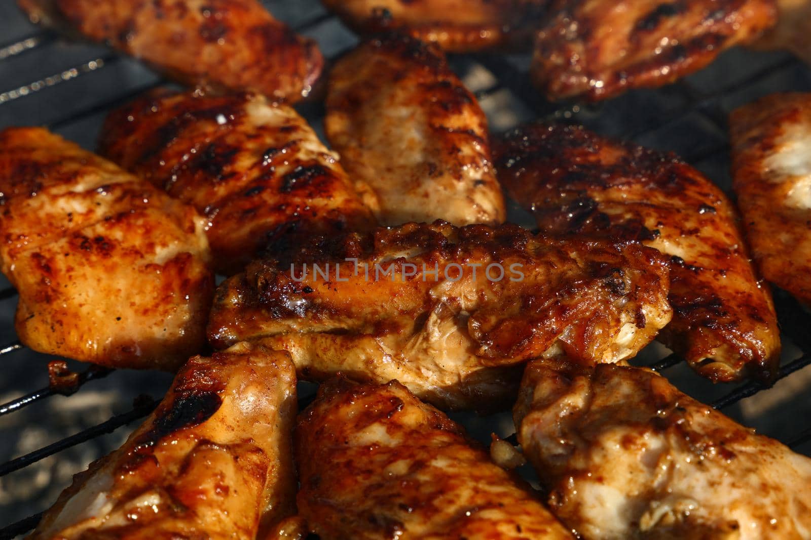 Close up cooking and smoking chicken buffalo or teriyaki sauce wings on bbq char grill, high angle view