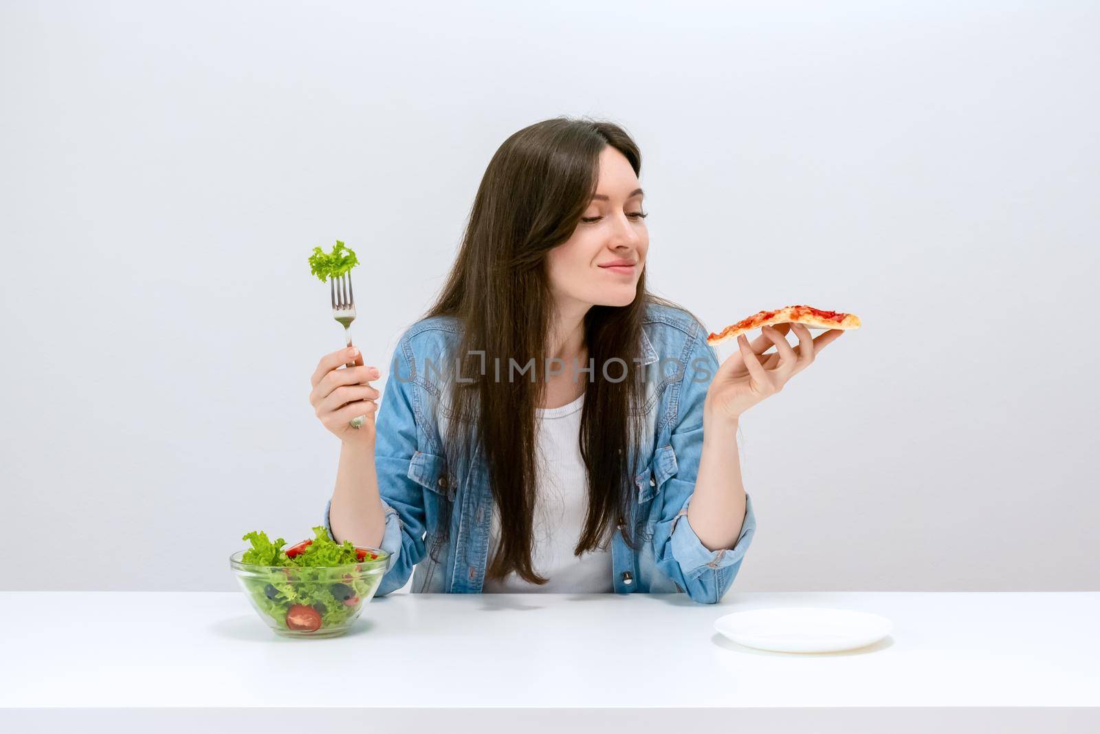 Young beautiful woman on a diet wants to choose pizza instead of salad by Svetlana_Belozerova